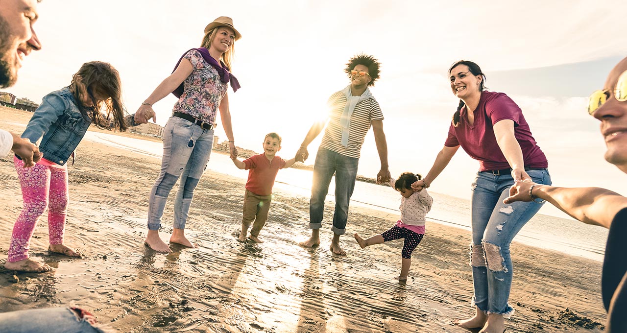 Kinder und Erwachsene am Strand halten sich an den Händen
