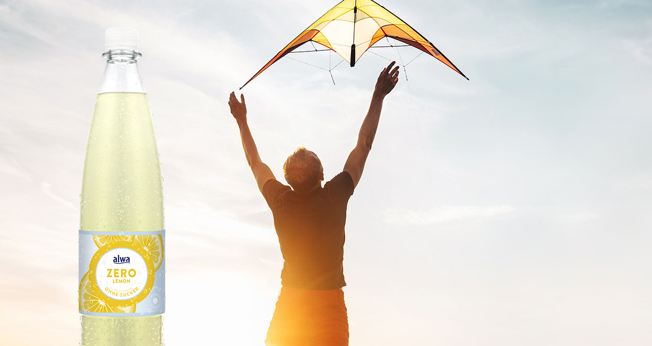 Mann mit Lenkdrache und Zitronenlimonade ohne Zucker in der Flasche