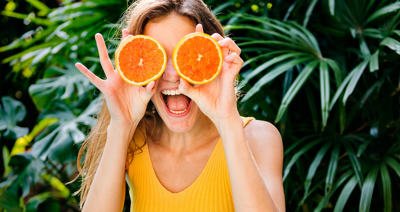 Frau hält sich Orangen vor die Augen