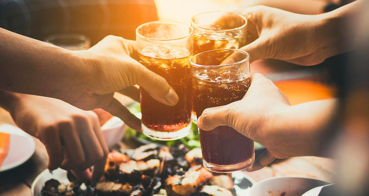 Hände, die mit Cola-Mix anstoßen