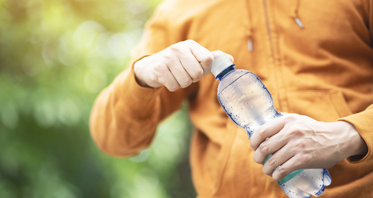Person dreht Mineralwasser medium Flasche auf