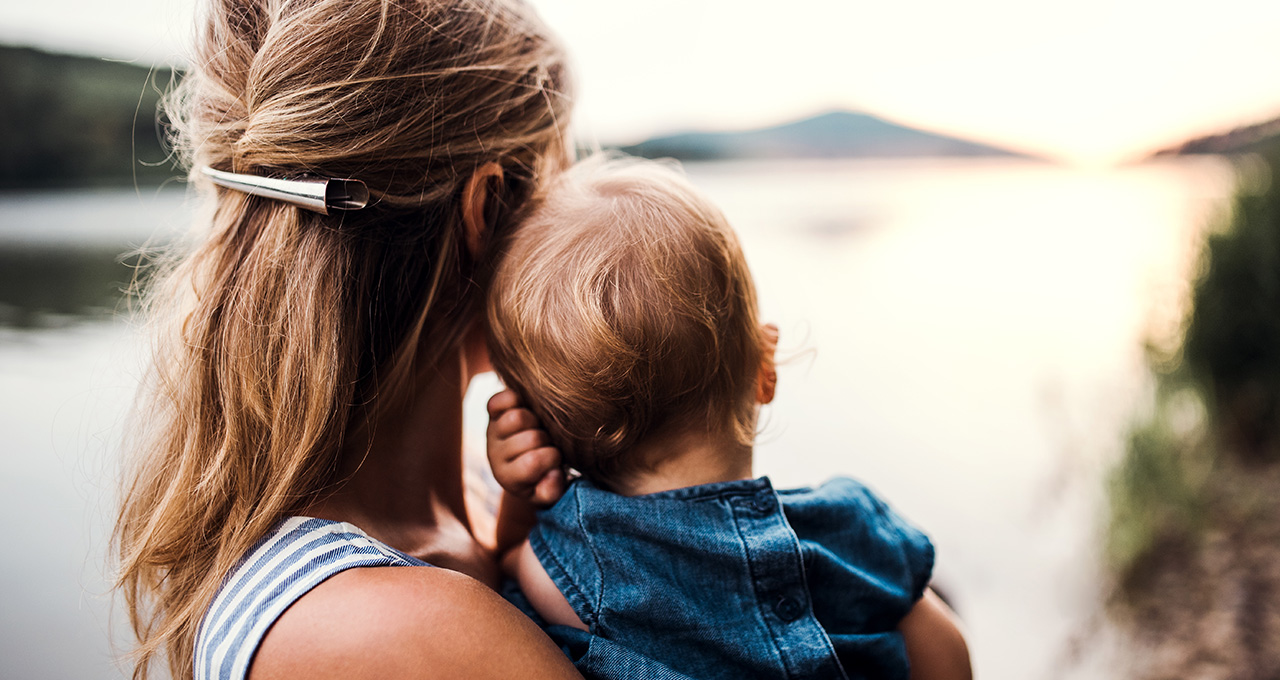 Frau mit Kind auf dem Arm von hinten
