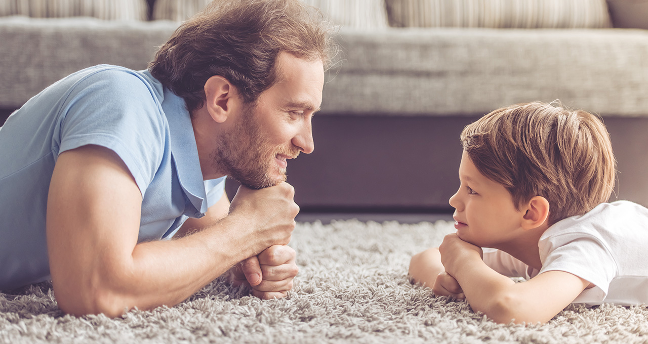 Mann und Junge liegen auf einem Teppich