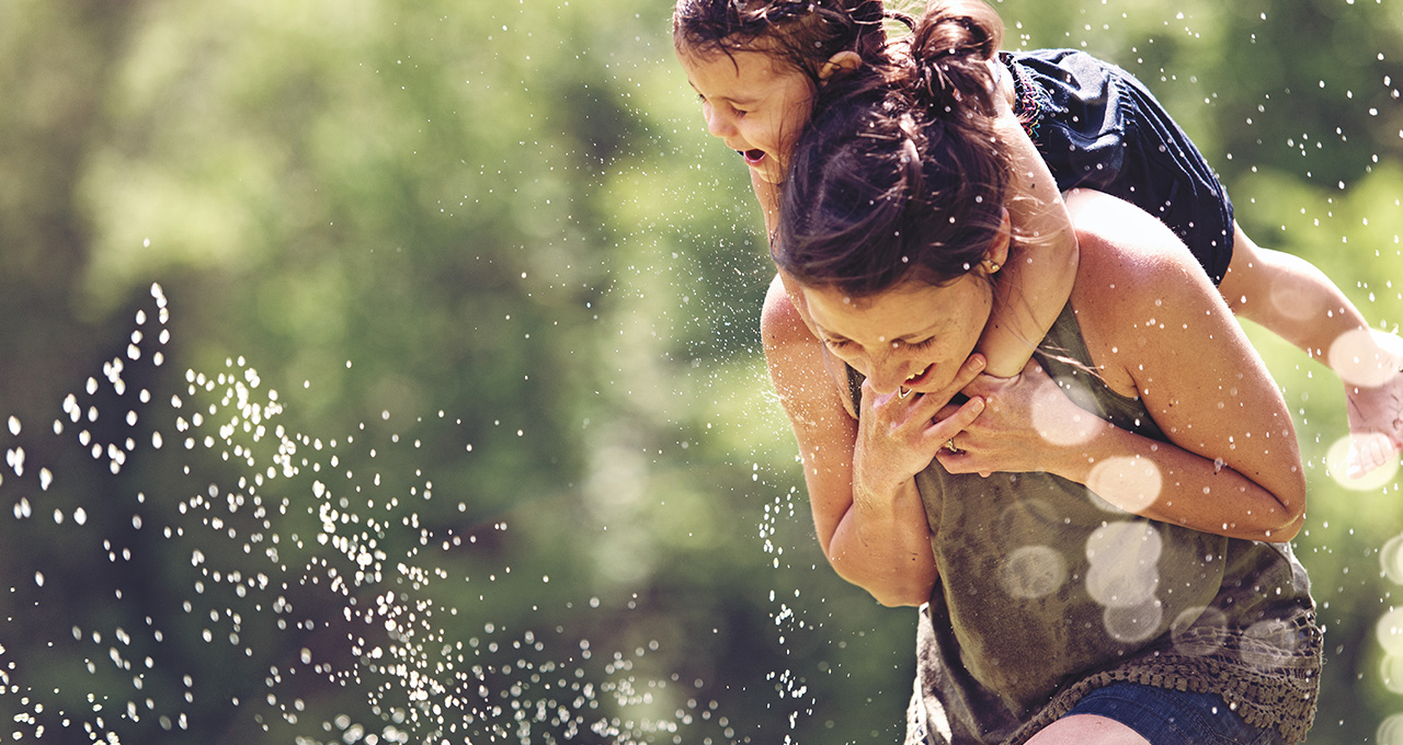 Lachende Frau mit Kind auf dem Rücken