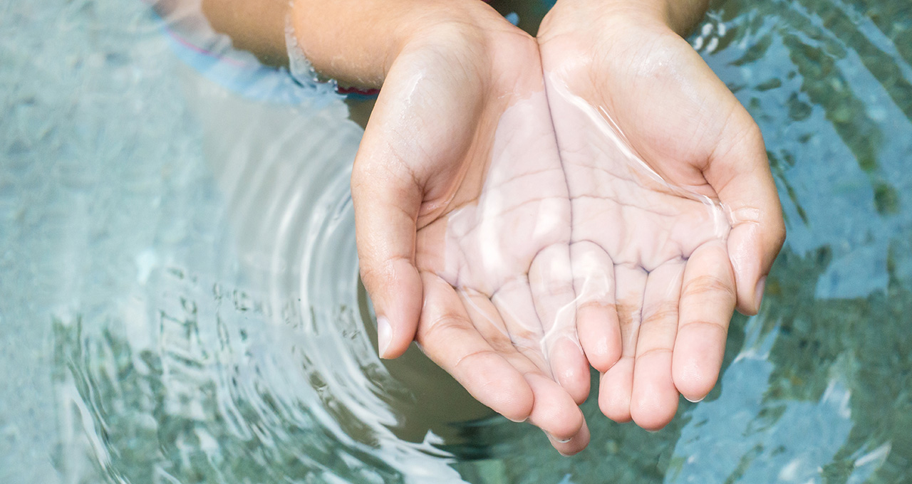 Hände tauchen in Wasser