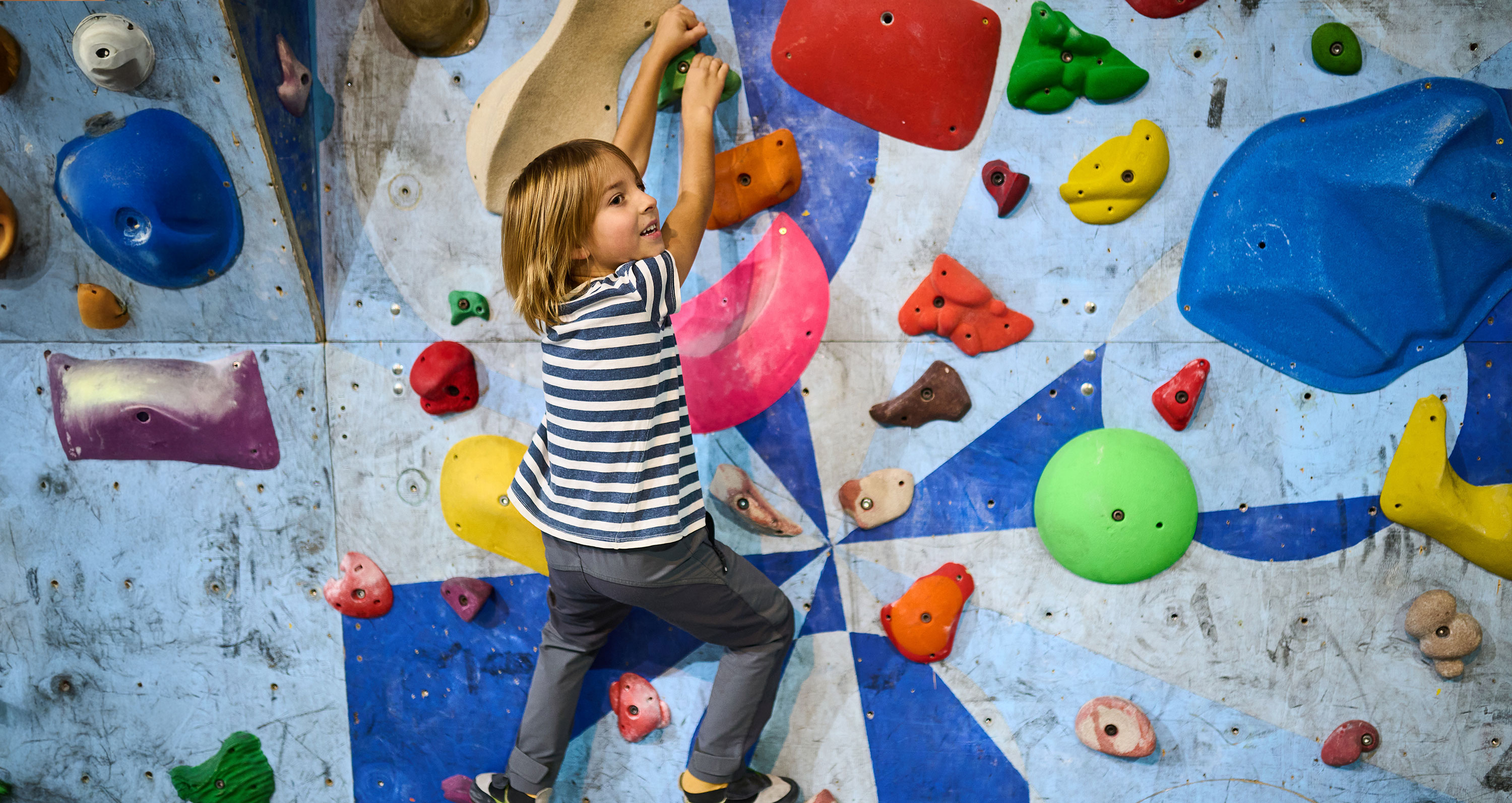 Kind an einer bunten Kletterwand