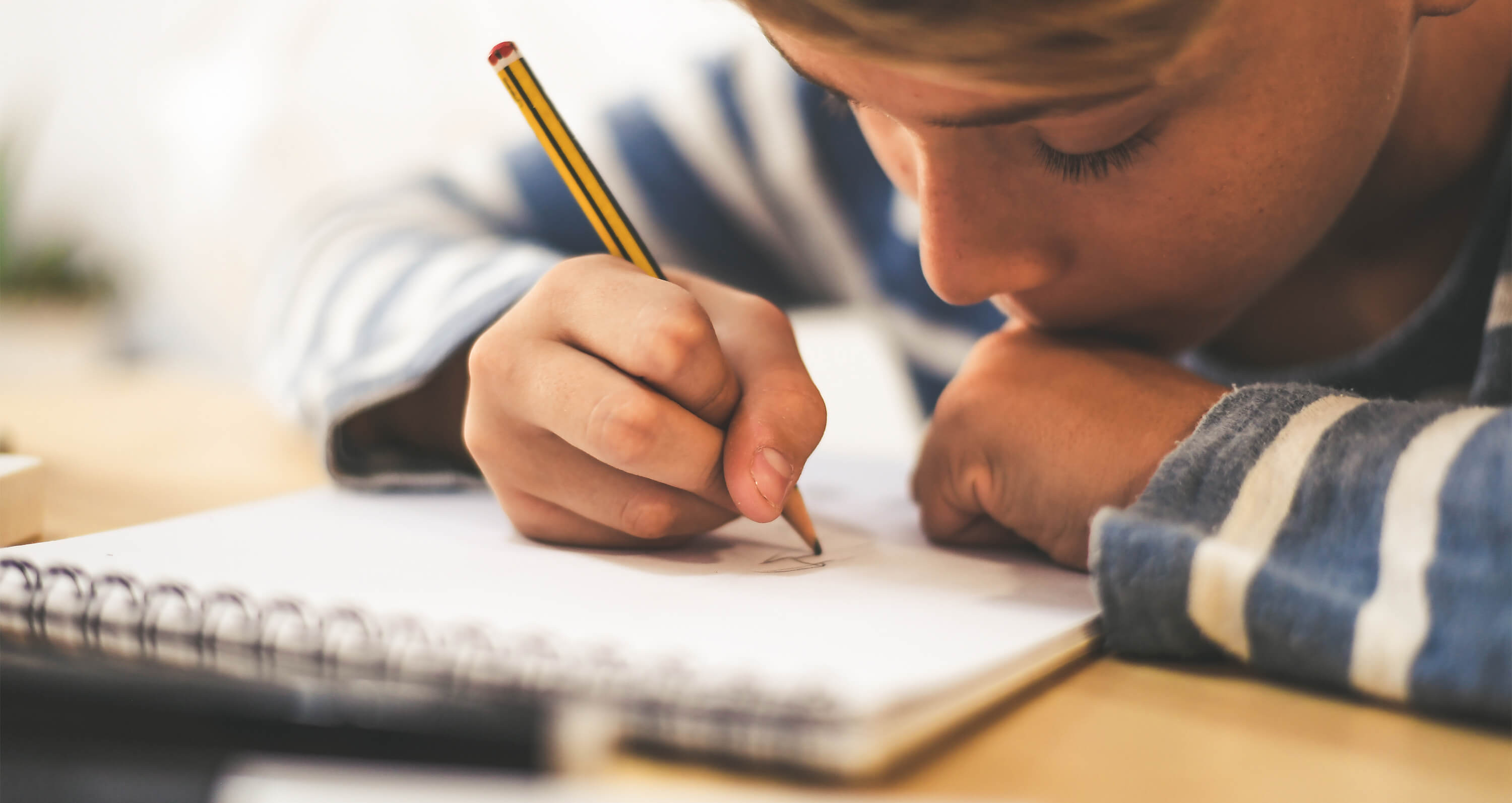 Junge schreibt mit Stift auf Block