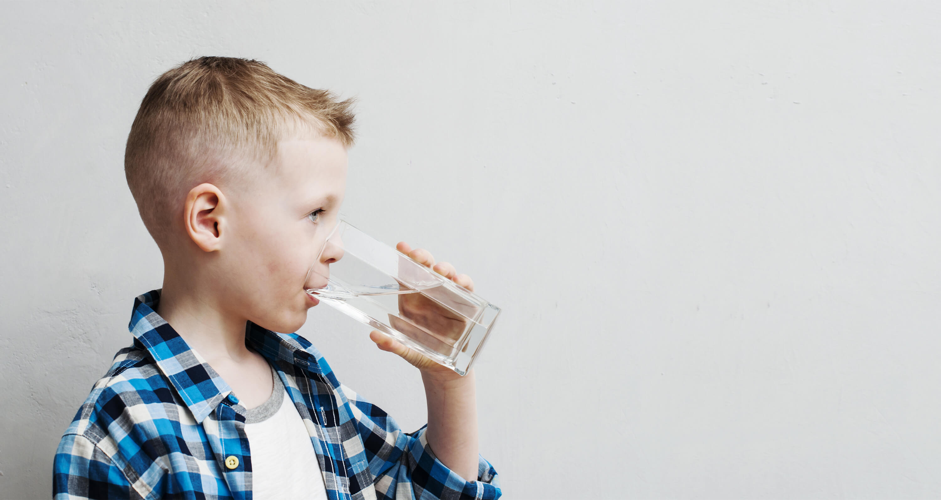 Kleiner Junge mit Mineralwasserglas in der Hand