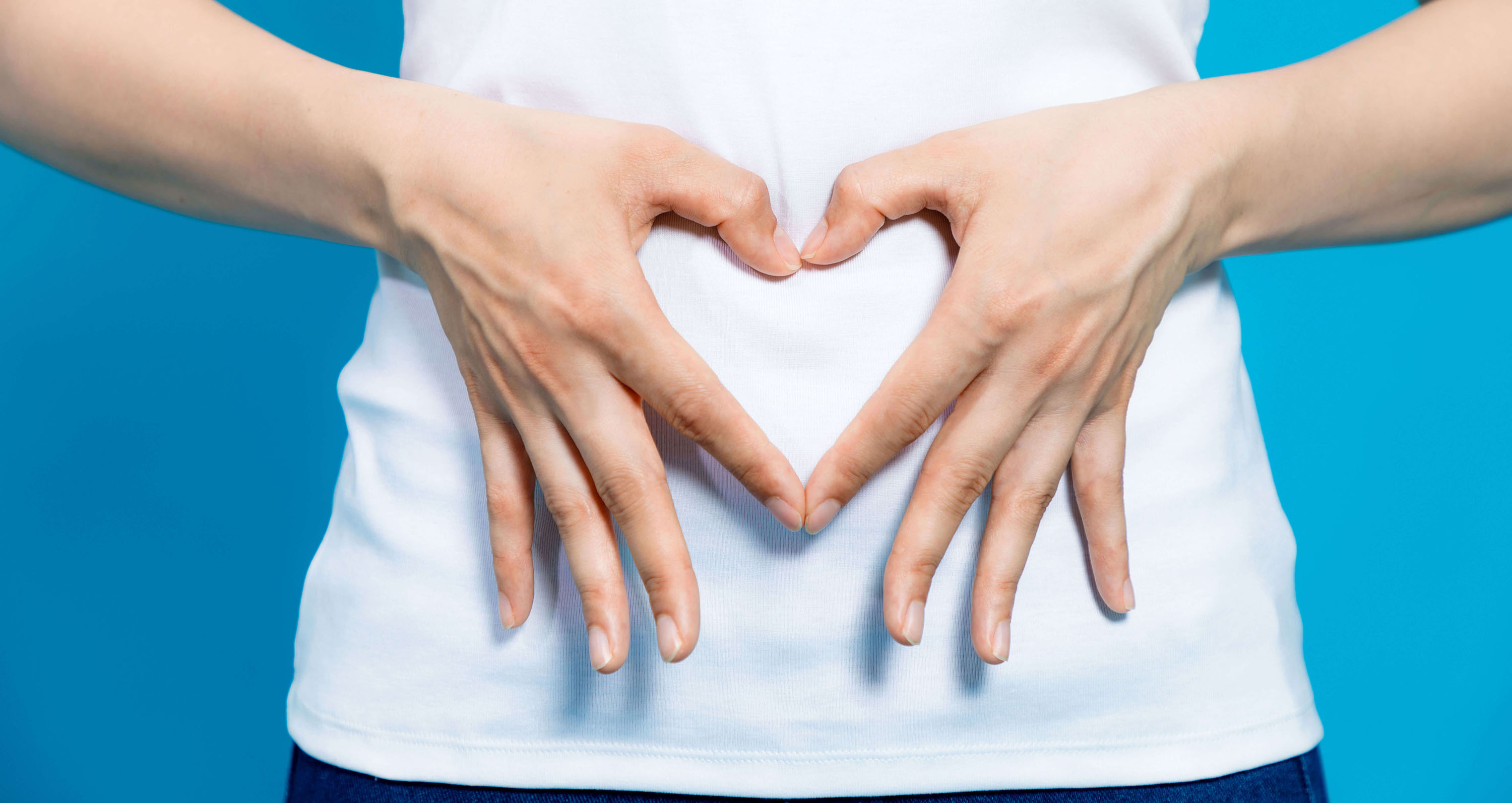 Hände, die ein Herz vor dem Bauch formen